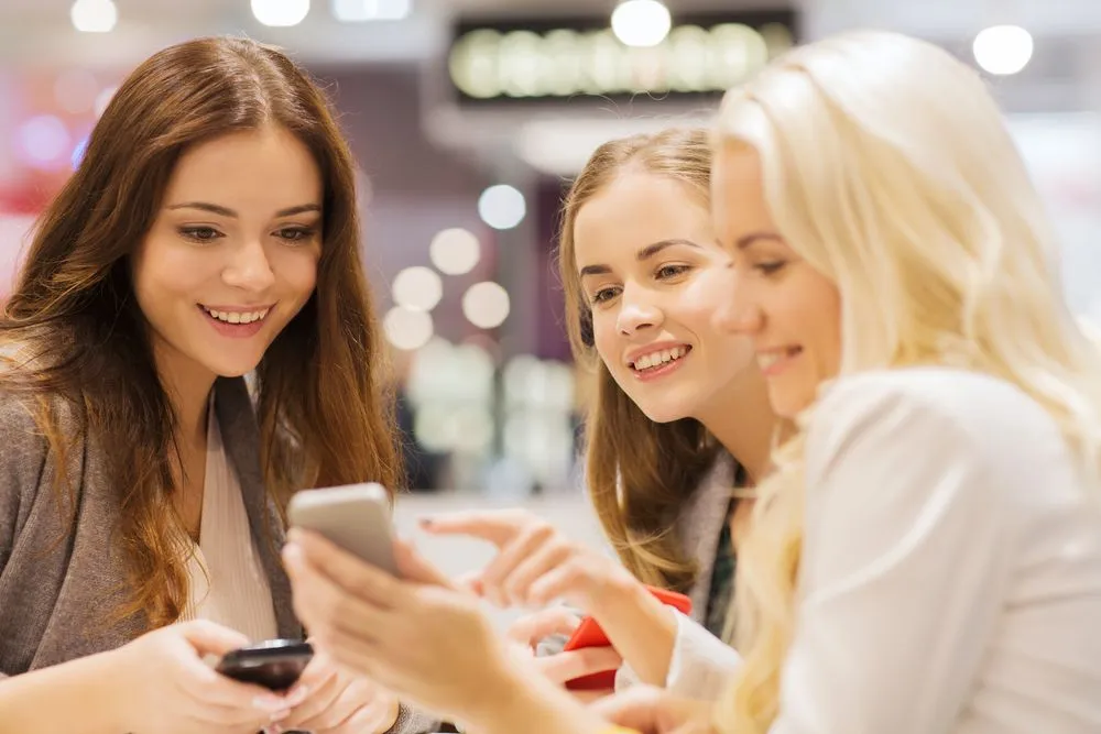 Happy young women looking and pointing on smartphones