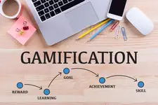 Office table with laptop, smartphone, pencils, cup of coffee and lettering in middle with the word 'GAMIFICATION'