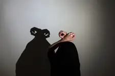 Play shadow projected on a white screen. the person's hands and head give shape to a monster.