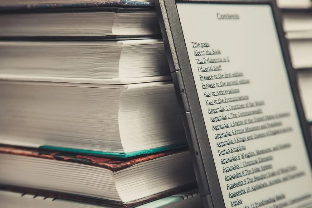 Close-up of stack of books with e-reader