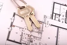 Two keys atop a paper house floor plan drawing